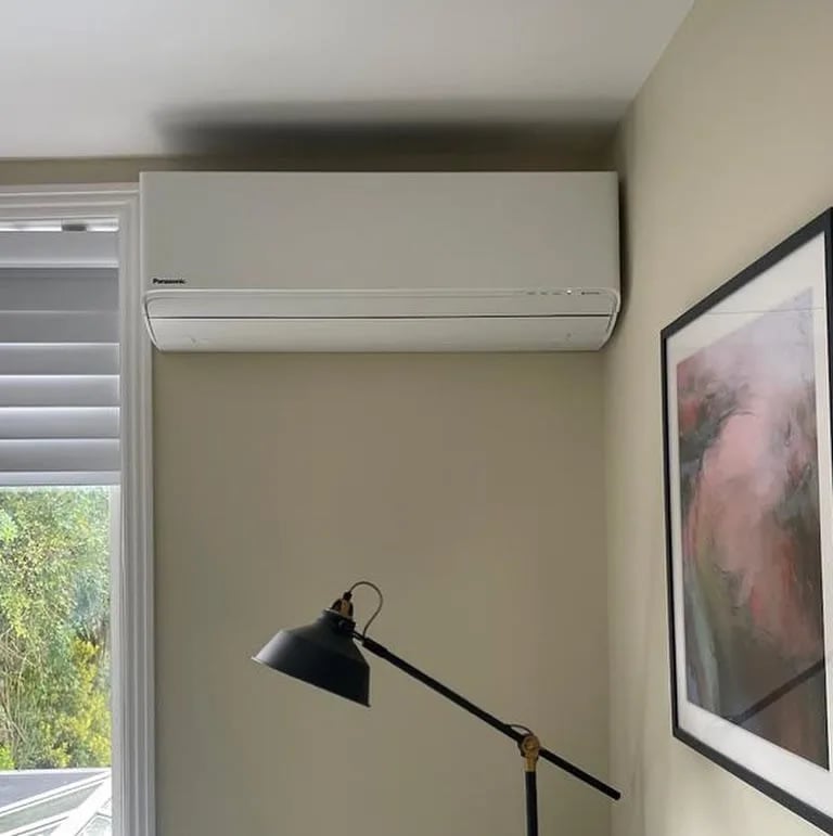 Panasonic wall unit installed high in a living space, blending in beside the window.