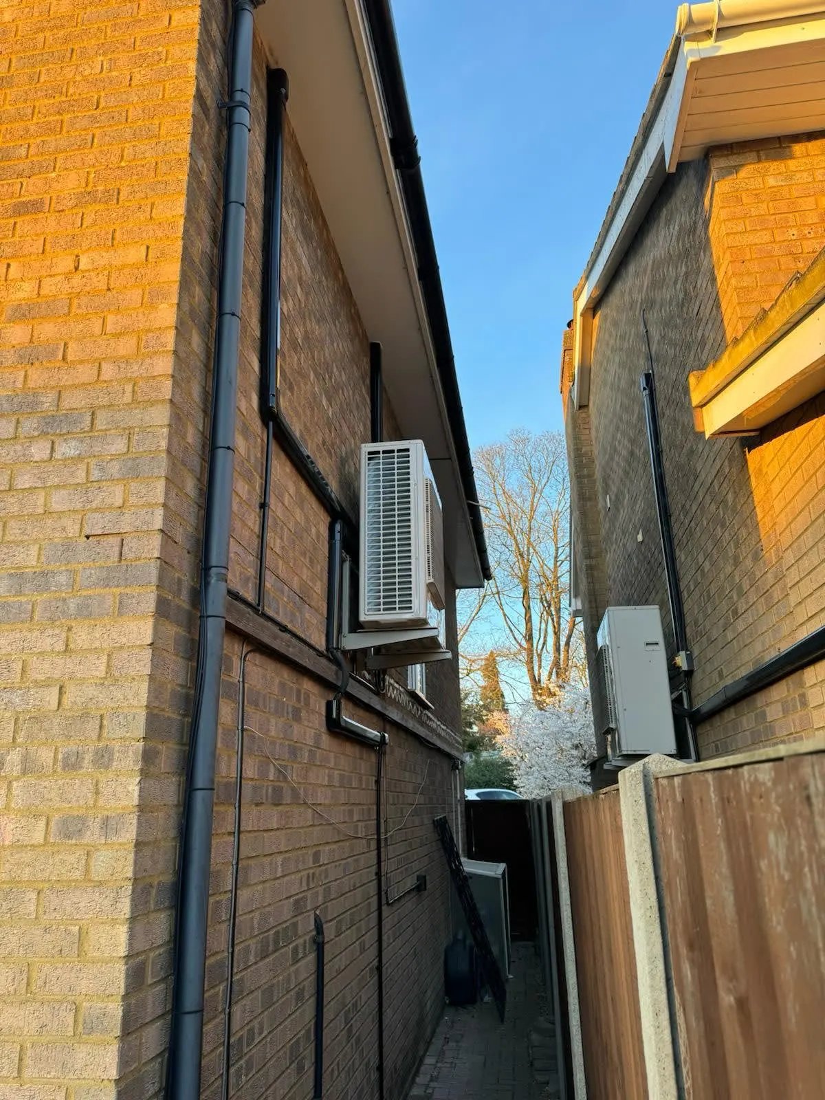Multiple outdoor units cleanly installed in the passage between two properties.